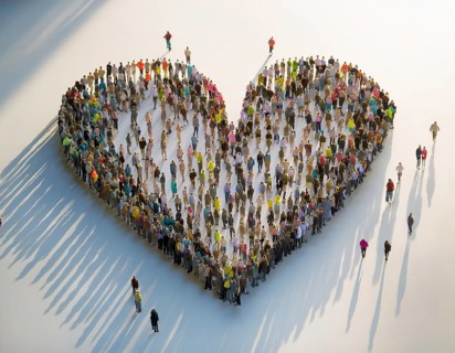 A diverse crowd of people standing together to form a heart shape, symbolizing community,
