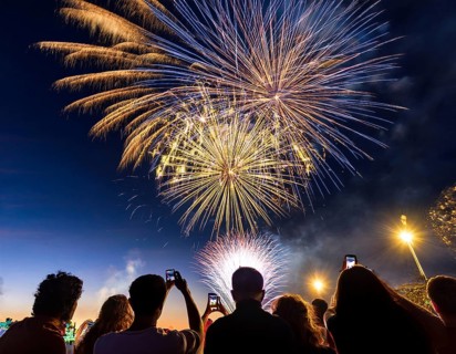 Thrilling fireworks illuminate the dark sky as a crowd gathers to enjoy the dazzling display,