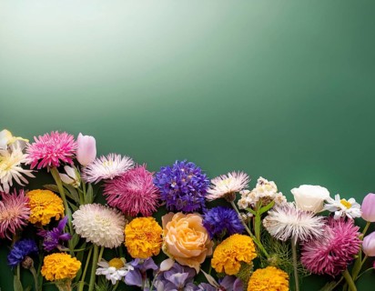 A variety of colorful wildflowers flourish on a hillside against a blurred mountainous backdrop.