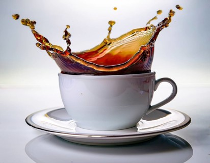 A visually dynamic splash of coffee leaping out of a sleek white cup, embodying energy and motion