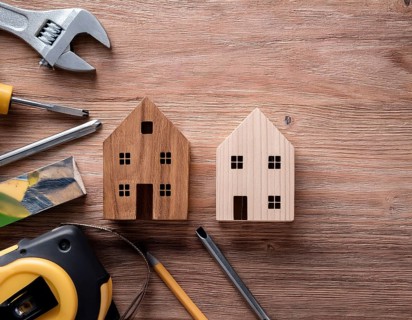 A detailed layout of miniature wooden houses accompanied by various tools on a textured wooden