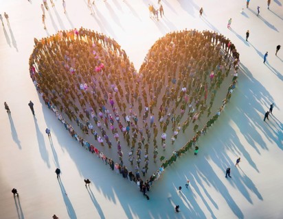 A diverse crowd of people standing together to form a heart shape, symbolizing community,