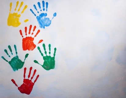 Brightly colored handprints in various hues arranged artistically on a textured white surface,