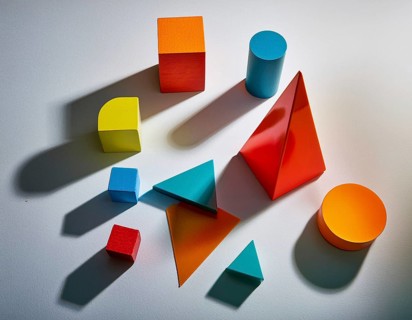 Vividly colored geometric shapes, including spheres and pyramids, artfully arranged on a surface.