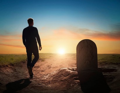 A silhouette of a lone figure walking off a gravestone, The scene evokes Resurrection thoughts