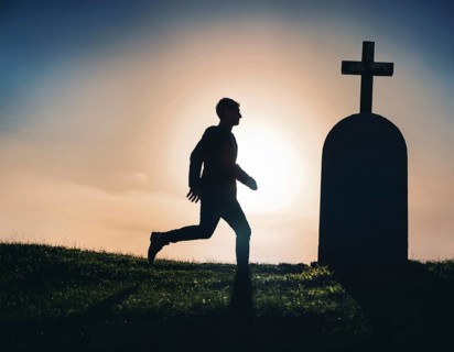 A silhouette of a lone figure walking off a gravestone, The scene evokes Resurrection thoughts
