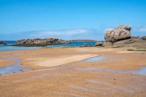Spectacular pink granite rocks, sculpted by wind and sea, pile up on the beach of the Cote de