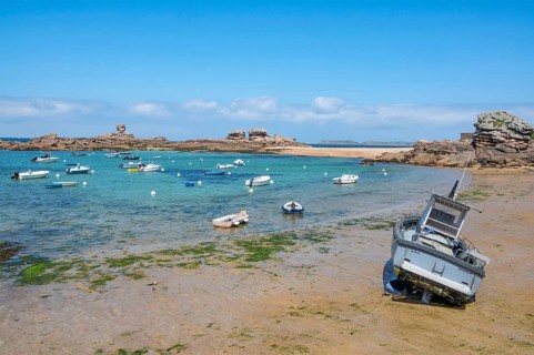 On the harbour beach of Tregastel on the Cote de Granit Rose, small boats lie on the light sand at