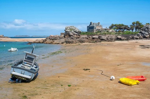 On the harbour beach of Tregastel on the Cote de Granit Rose, small boats lie on the light sand at