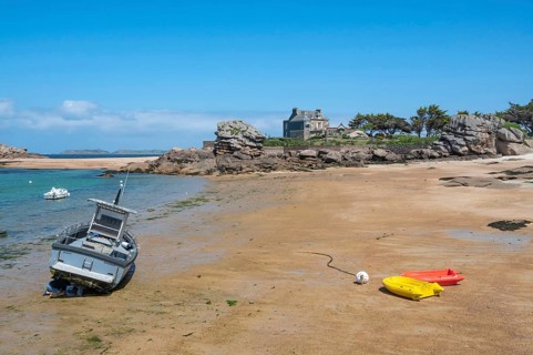 On the harbour beach of Tregastel on the Cote de Granit Rose, small boats lie on the light sand at