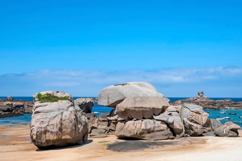 Spectacular pink granite rocks, sculpted by wind and sea, pile up on the beach of the Cote de