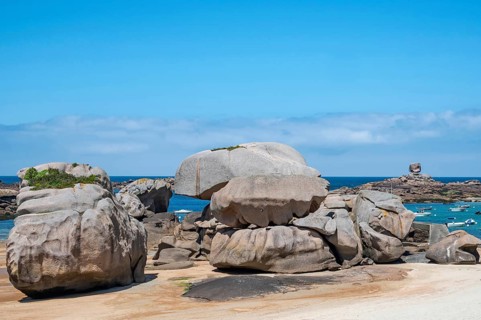 Spectacular pink granite rocks, sculpted by wind and sea, pile up on the beach of the Cote de