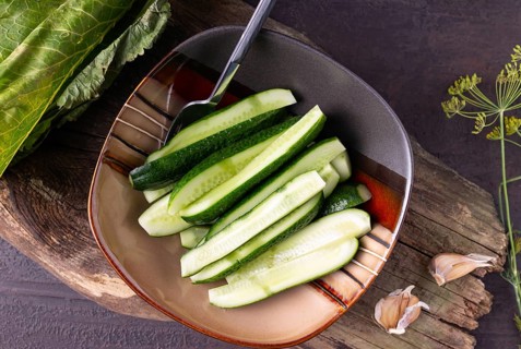 Lightly salted cucumbers in a square plate on a wooden background