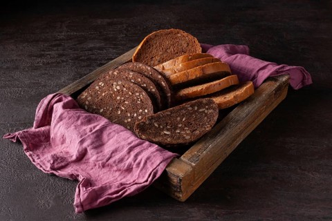 Healthy bread with sprouted grains lies in a wooden box on a pink cloth