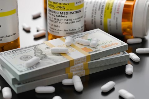 Prescription medicine bottles and pills next to stacks of 100 dollar bills
