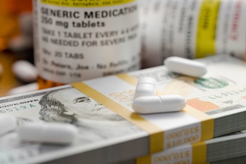 Prescription medicine bottles and pills next to stacks of 100 dollar bills