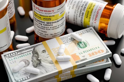 Prescription medicine bottles and pills next to stacks of 100 dollar bills