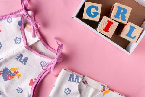 Clothes for a newborn girl and wooden cubes with letters Girl