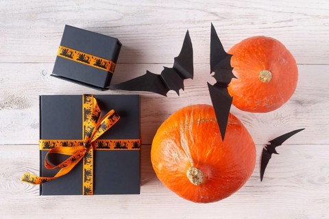 Pumpkin gifts black paper bats on light wood flat lay halloween decor
