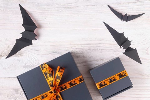 A pair of gray boxes tied with an orange ribbon, with drawings on the theme of Halloween copy space