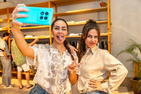 Two friends are having fun taking a selfie with a smartphone, sticking out their tongues, in a