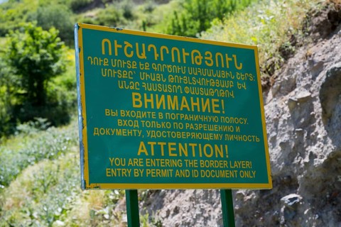 A multilingual warning sign regulating access to the border zone, sign in front of a military post