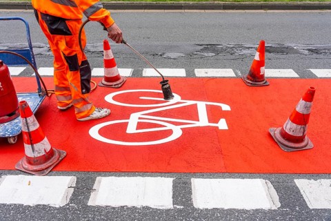 Application of red road surfacing on a cycle lane, inner-city road, so-called cold plastic