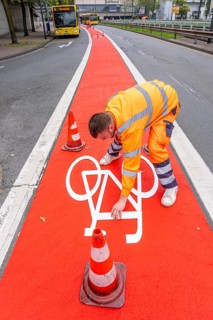 Application of red road surfacing on a cycle lane, inner-city road, so-called cold plastic