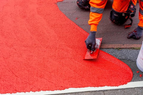 Application of red road surfacing on a cycle lane, inner-city road, so-called cold plastic