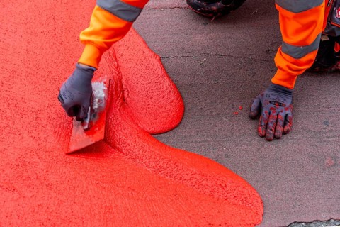 Application of red road surfacing on a cycle lane, inner-city road, so-called cold plastic