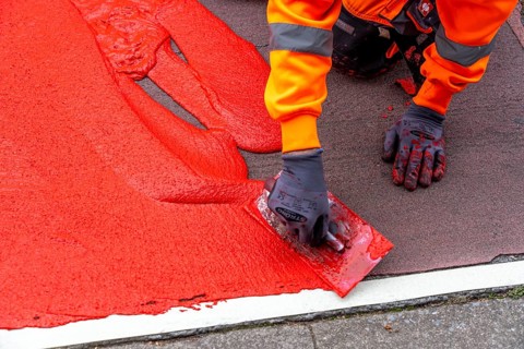 Application of red road surfacing on a cycle lane, inner-city road, so-called cold plastic