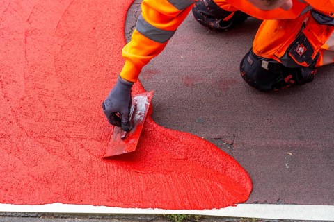 Application of red road surfacing on a cycle lane, inner-city road, so-called cold plastic