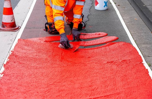 Application of red road surfacing on a cycle lane, inner-city road, so-called cold plastic