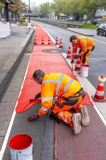 Application of red road surfacing on a cycle lane, inner-city road, so-called cold plastic