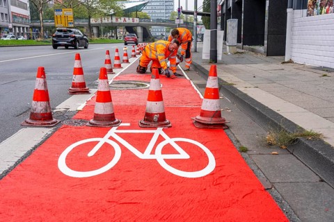Application of red road surfacing on a cycle lane, inner-city road, so-called cold plastic