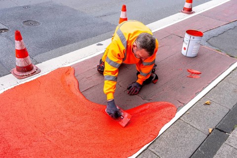 Application of red road surfacing on a cycle lane, inner-city road, so-called cold plastic