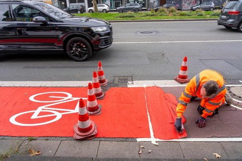 Application of red road surfacing on a cycle lane, inner-city road, so-called cold plastic