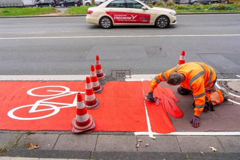 Application of red road surfacing on a cycle lane, inner-city road, so-called cold plastic