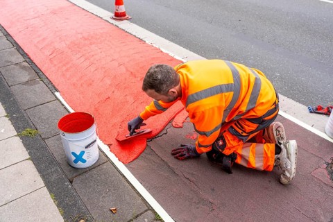 Application of red road surfacing on a cycle lane, inner-city road, so-called cold plastic