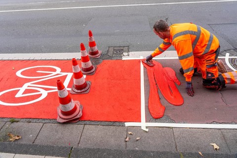 Application of red road surfacing on a cycle lane, inner-city road, so-called cold plastic