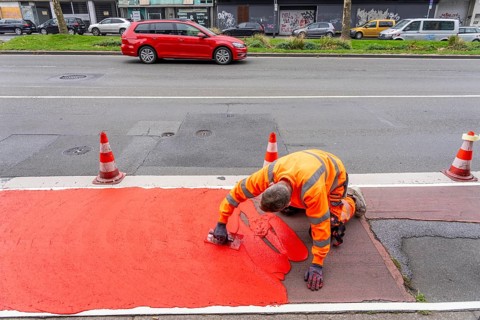Application of red road surfacing on a cycle lane, inner-city road, so-called cold plastic