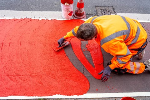 Application of red road surfacing on a cycle lane, inner-city road, so-called cold plastic