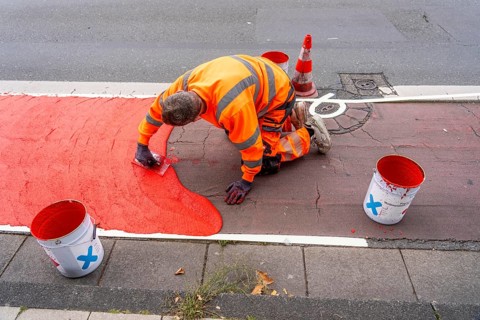 Application of red road surfacing on a cycle lane, inner-city road, so-called cold plastic