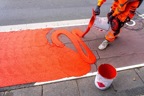Application of red road surfacing on a cycle lane, inner-city road, so-called cold plastic