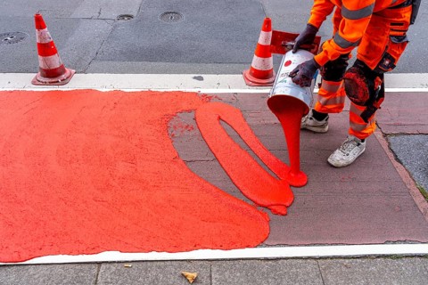 Application of red road surfacing on a cycle lane, inner-city road, so-called cold plastic