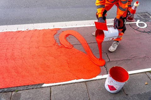 Application of red road surfacing on a cycle lane, inner-city road, so-called cold plastic
