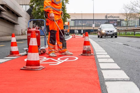 Application of red road surfacing on a cycle lane, inner-city road, so-called cold plastic