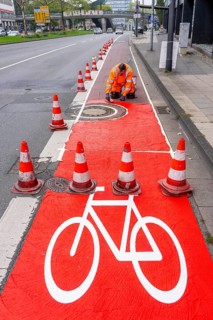 Application of red road surfacing on a cycle lane, inner-city road, so-called cold plastic