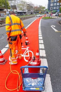 Application of red road surfacing on a cycle lane, inner-city road, so-called cold plastic