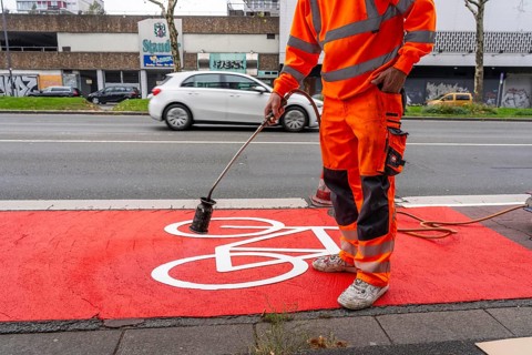 Application of red road surfacing on a cycle lane, inner-city road, so-called cold plastic